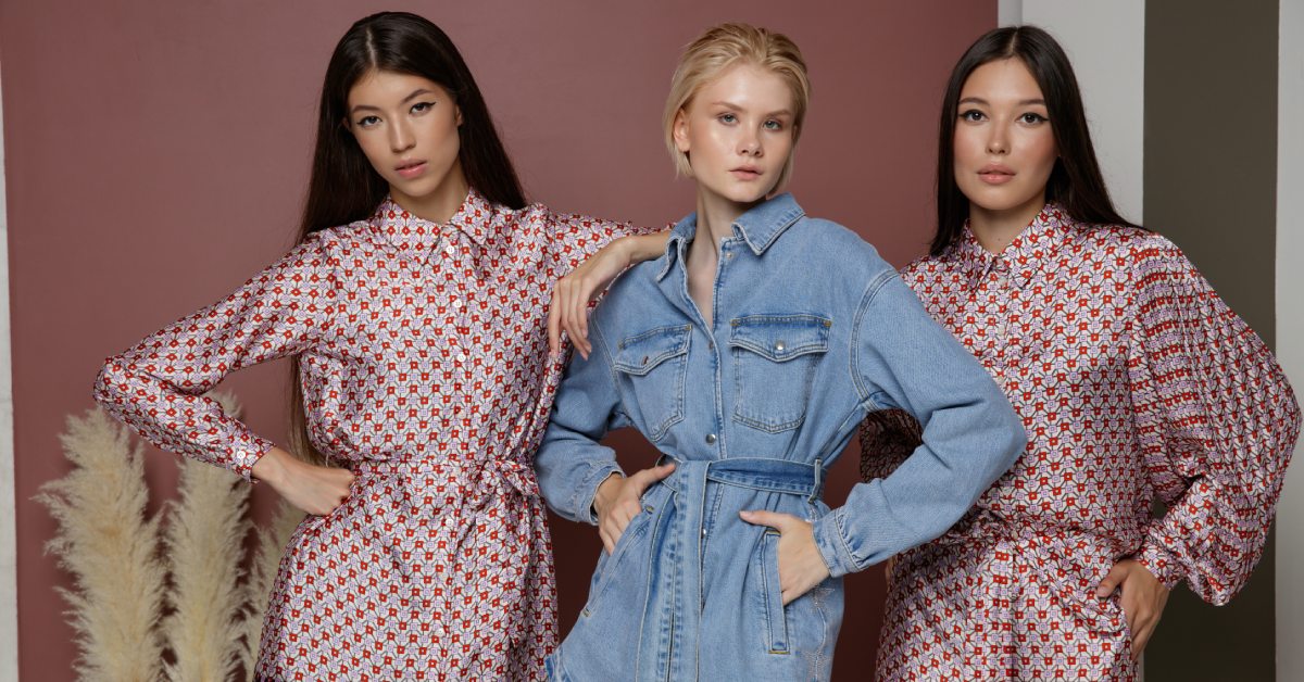 Three fashion models--one wearing a dress, one wearing a romper, and one wearing a jumpsuit--all pose for the camera.